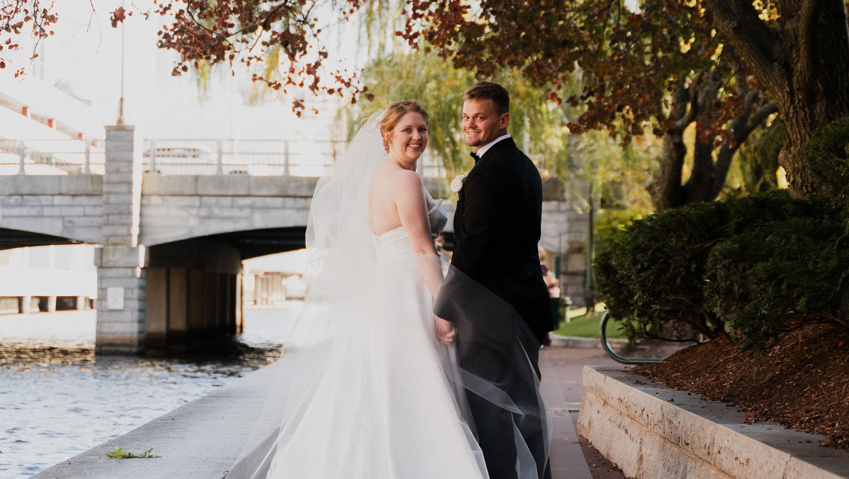 Newlyweds posing by bridge in Cambridge